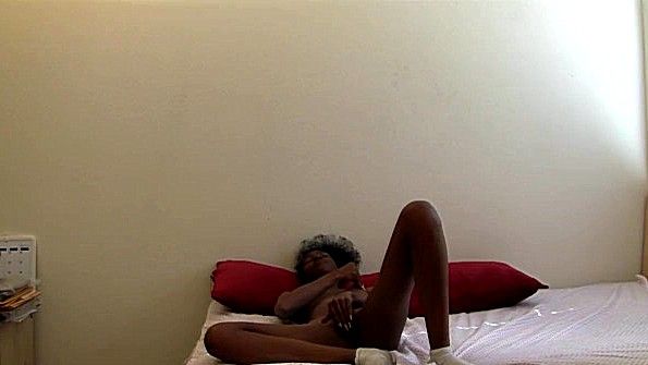 Негритянка лежит в кровати и отчаянно дрочит пизду