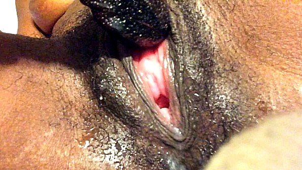 Негритянка неторопливо водит вибратором по пизде